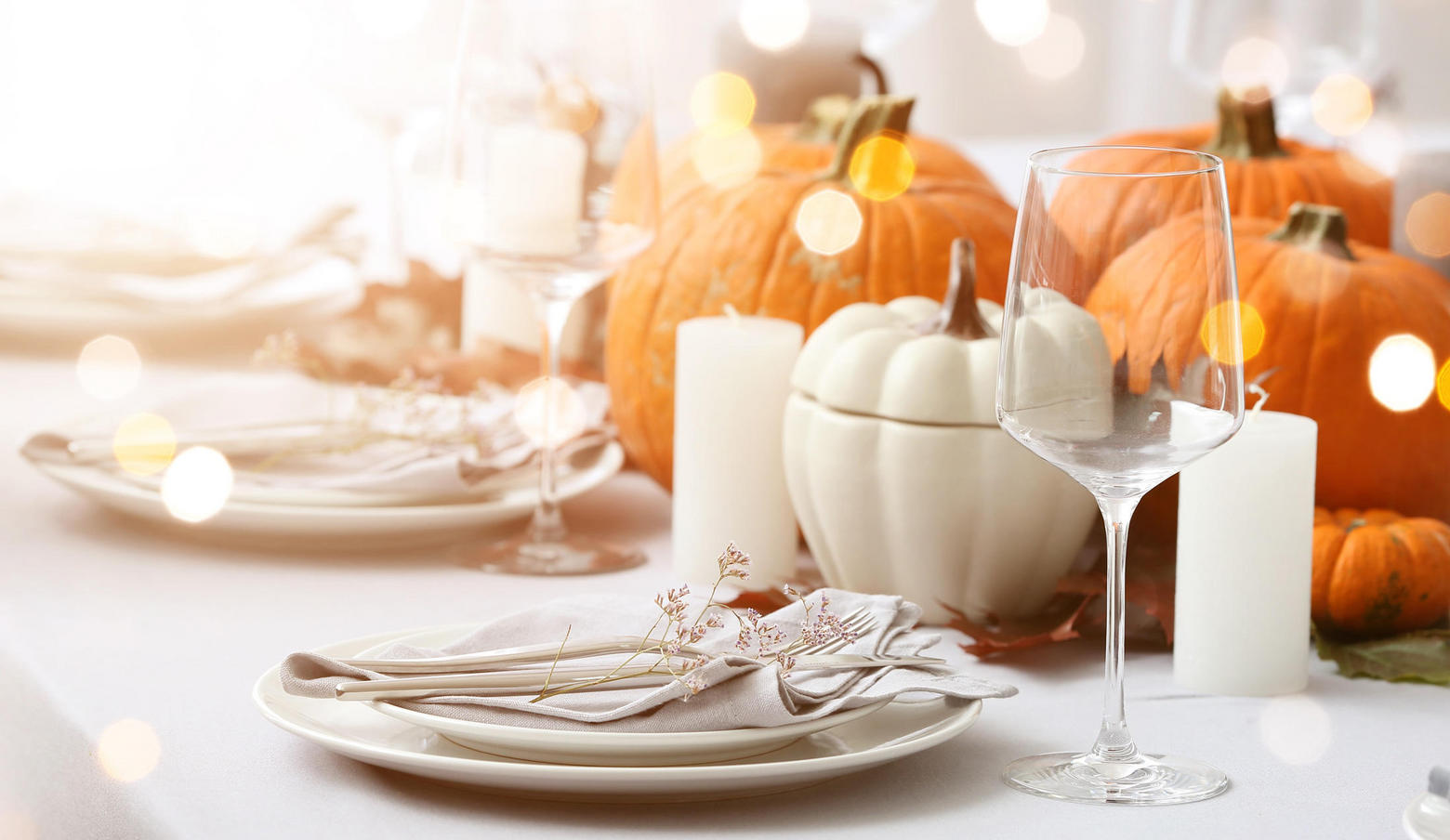 Fall table setting with pumpkins, place settings and candles